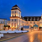 Kurhaus Binz<br>
Ab 1907 nach Plänen des Berliner Architekten Otto Spalding gebaut, ist das Kurhotel seit über 100 Jahren das dominante Wahrzeichen von Binz. Die notwendigen Rekonstruktionen und Modernisierungen in den 1990er Jahren ebneten den Weg für ein heutiges Luxushotel.<br>
(Abend am Kurhaus Rügen Binz, © World Travel images  Fotolia.com)